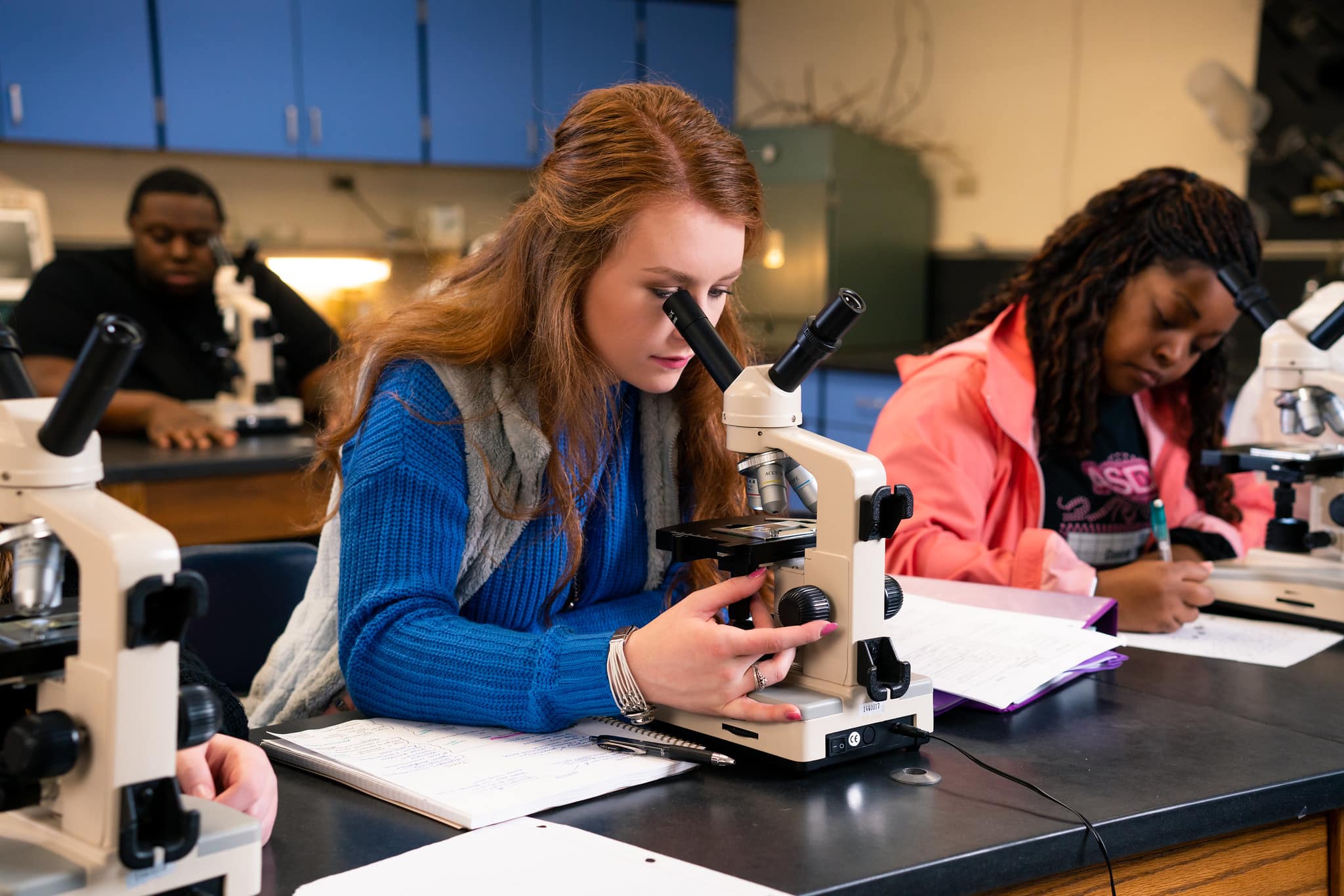 Student in biology lab looking through microscope