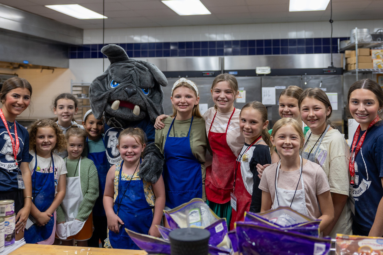Kids College culinary students gather with Bo the Bulldog for a group photo after a day of learning.