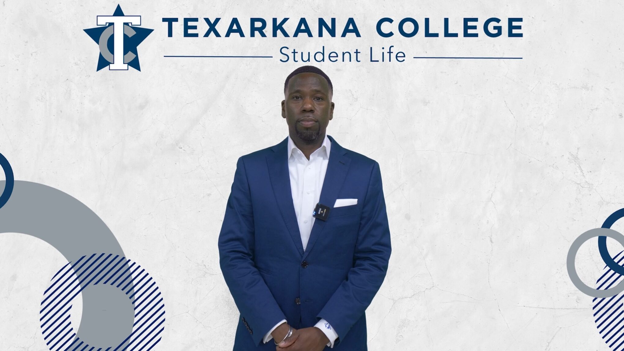 A man in a blue suit stands in front of a white background with the text Texarkana College Student Life and abstract blue-gray shapes.